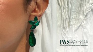 Woman showing the other half of her ear wearing an emerald pear drop earring 