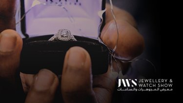 A person holding a halo setting engagement ring in its box 