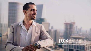 Man wearing a gold and blue watch looking sideways while posing on rooftop 