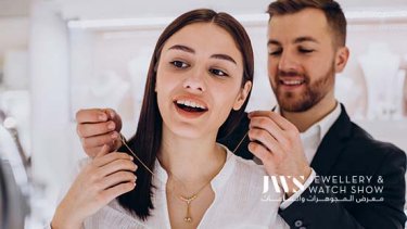 Man putting a gold necklace on a woman 