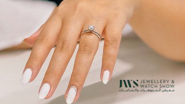 Simple setting engagement ring worn by a person with white nail polish 