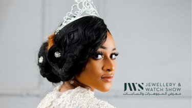 Woman posing sideways wearing a silver-colored crown and white dress 