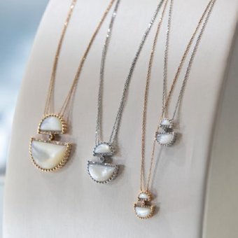 two silver and two gold necklaces on display