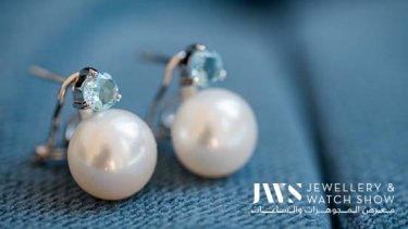 pearl earrings placed over aqua blue cloth