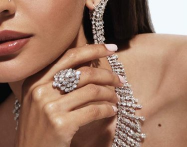 a lady wearing a diamond ring, necklace, and earrings