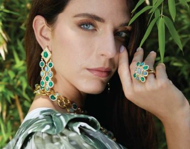 a green-eyed lady wearing green dangle earrings, bracelet, and necklace