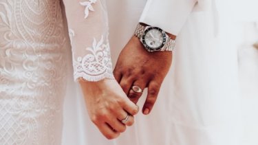 Close up of bride and groom holding hands