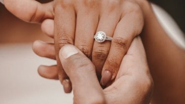Man's hand holding a woman's hand with engagement ring 