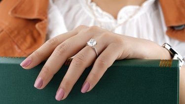 Woman wearing diamond ring and holding a book