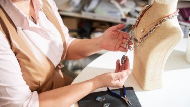 Female jeweller inspecting her handcrafted piece of jewellery