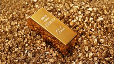 Gold bars laid over pile of nuggets