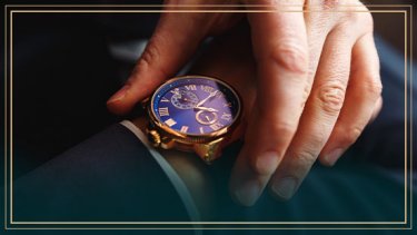 A hand holding a gold watch